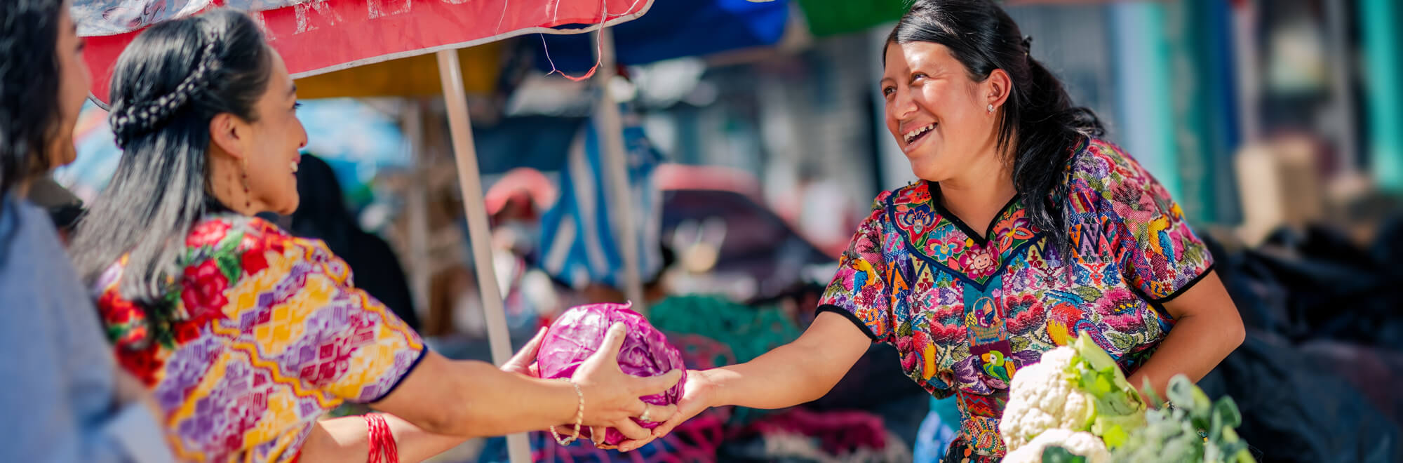 two women barter at a market stall
